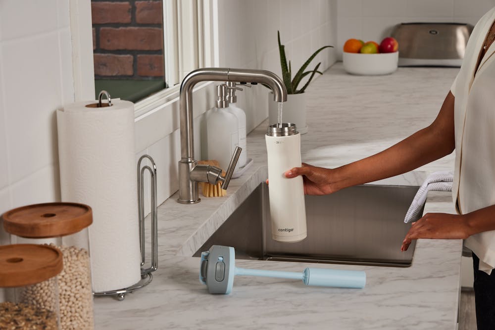 Person filling water bottle at a kitchen sink